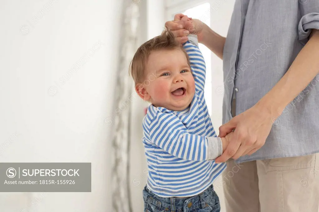 Laughing baby boy hand in hand with his mother