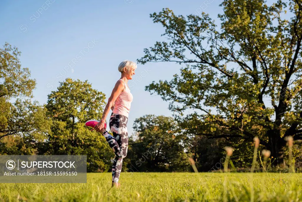 Senior woman stretching on rural meadow