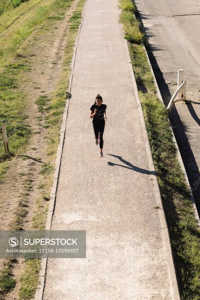 Sportive young woman running on a path
