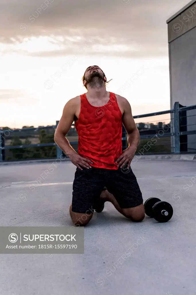 Exhausted athlete kneeling on ground after workout