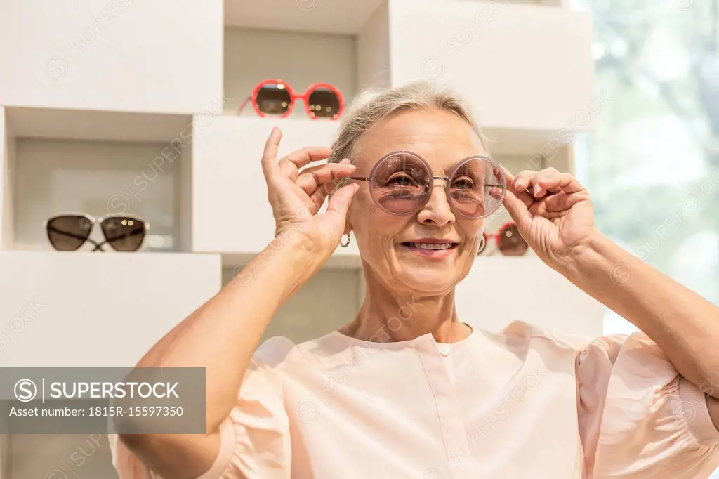 Smiling senior woman trying on sunglasses in a boutique