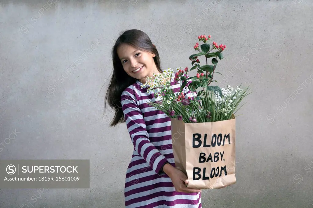 Portrait of happy girl holding paper bag with flowers