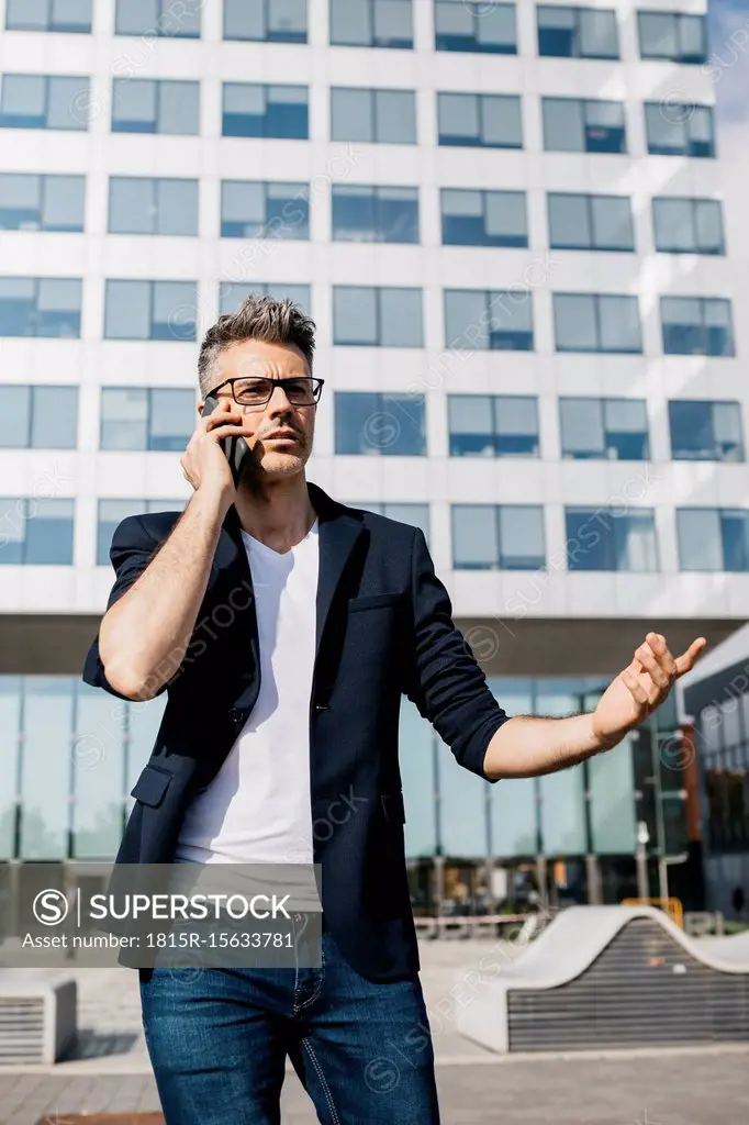 Angry businessman on cell phone walking outside office building