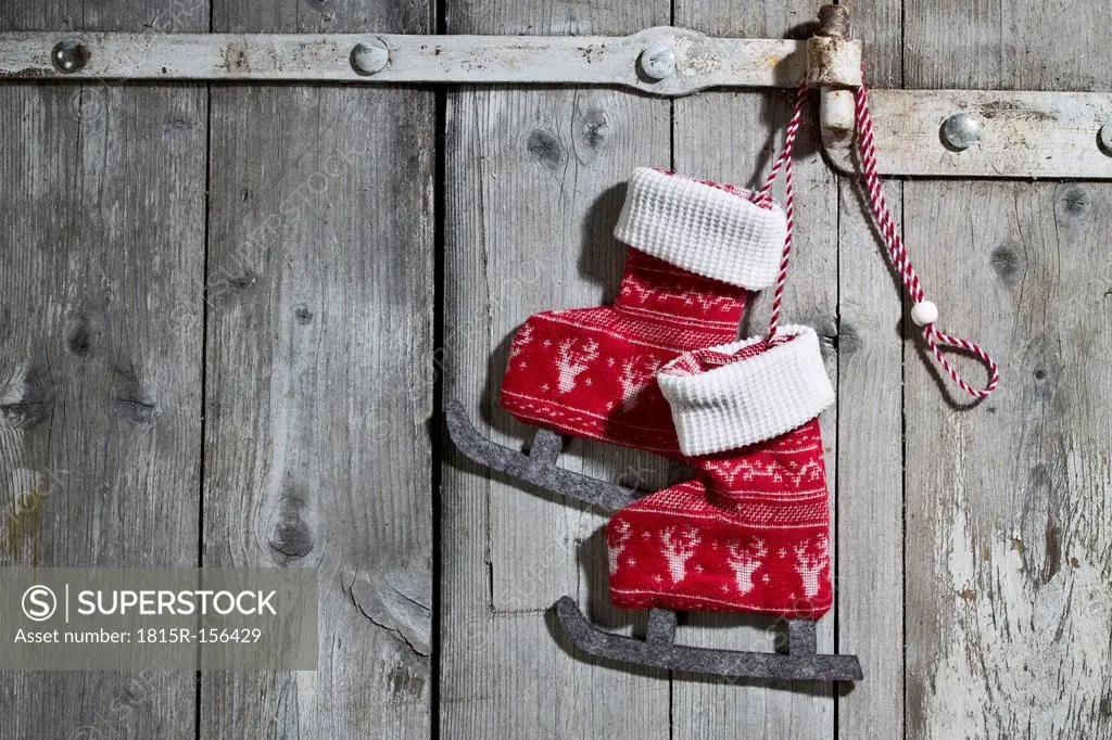 Pair of decorative textile ice skates hanging on wooden door