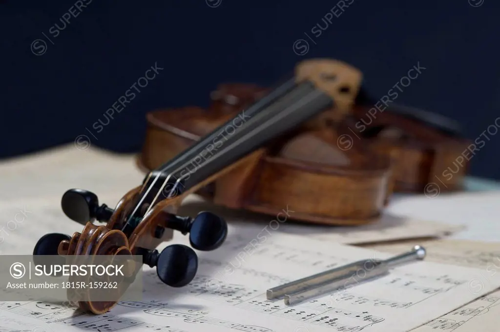 Antique violin and tuning fork lying on musical notes