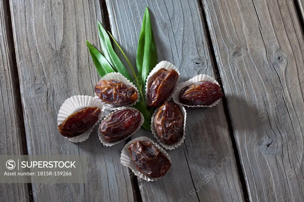 Seven dates in paper cups on wooden table