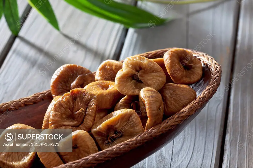 Wooden bowl with dried figs on wooden table