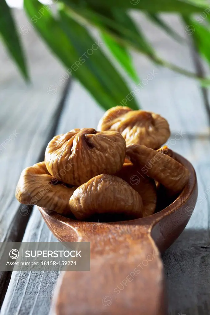 Wooden spoon with dried figs on wooden table