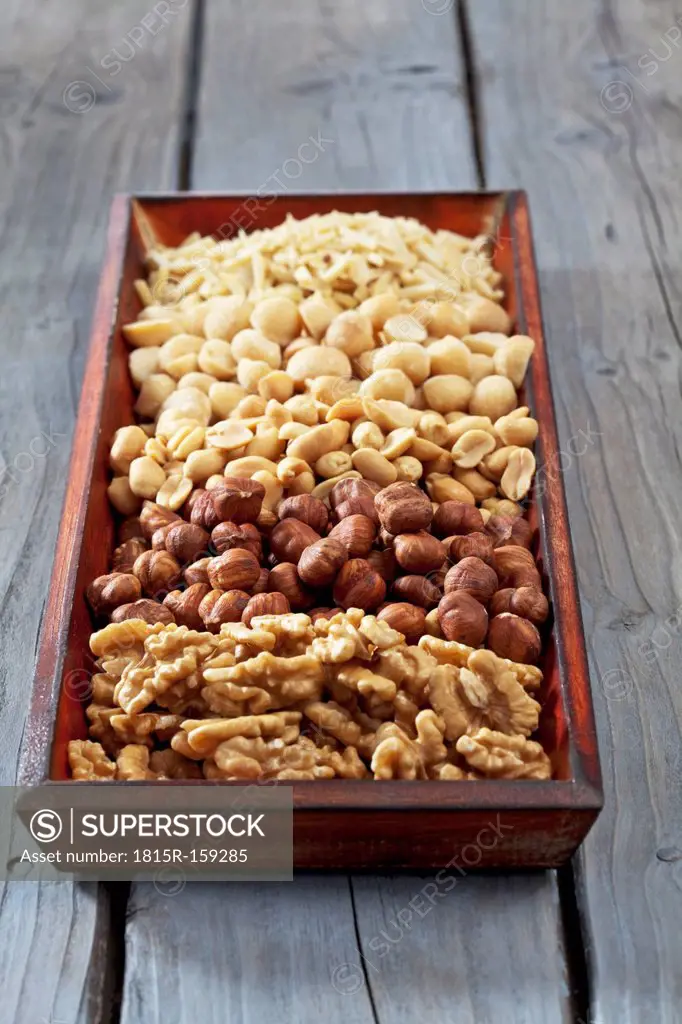 Wooden tray with different nuts on wooden table