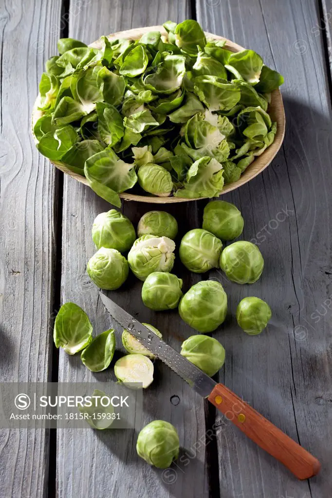 Brussels sprouts, plate with peels and kitchen knife on grey wooden table