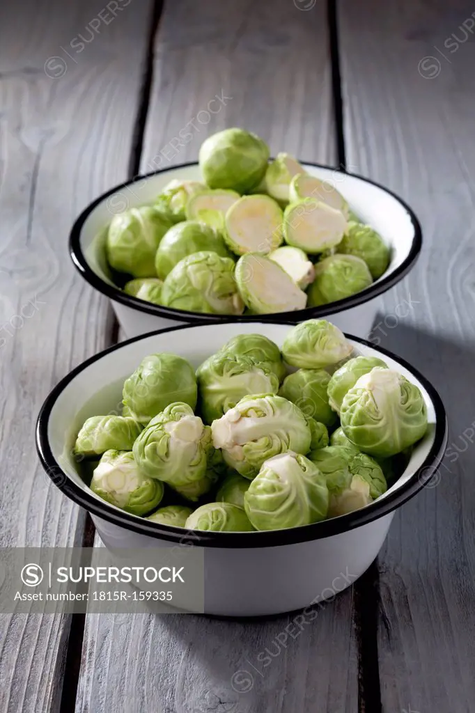 Two bowls of Brussels sprouts on grey wooden table
