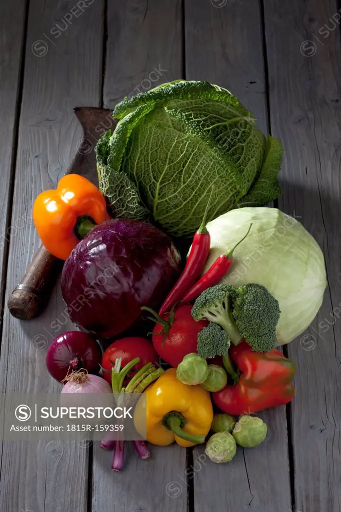 Cabbage varieties, other vegetables and antique knife on grey wooden table