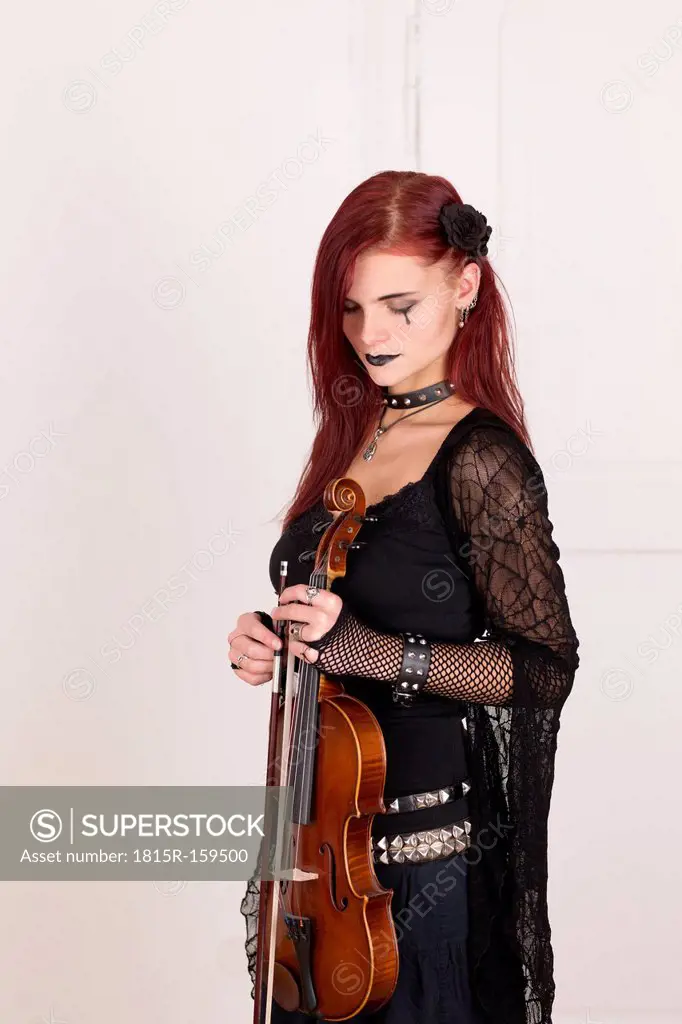 Young woman with closed eyes dressed in Gothic style holding violin