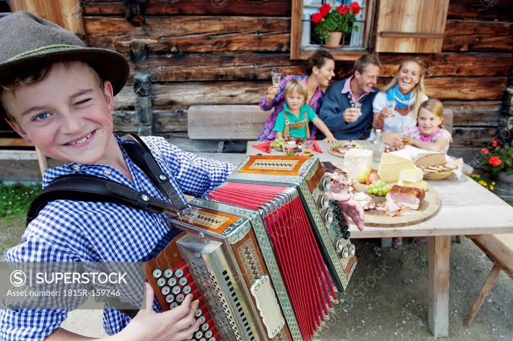 Austria, Salzburg State, Altenmarkt-Zauchensee, family having an alpine picnic while young boy playing accordion