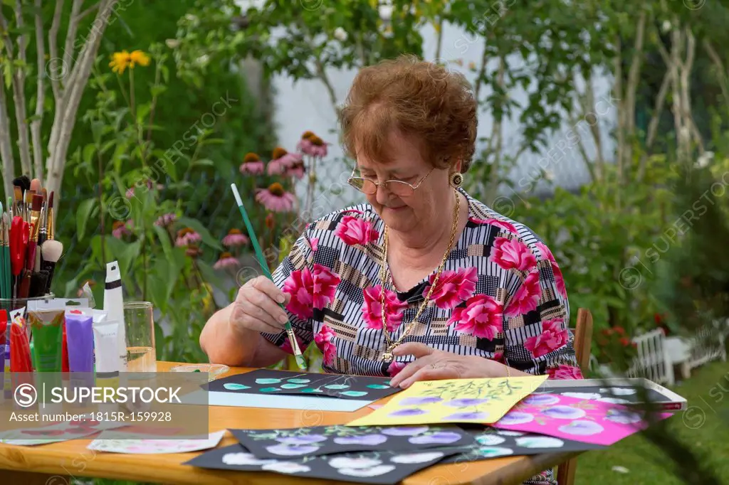 Germany, Bavaria, Ingolstadt, senior woman painting in garden