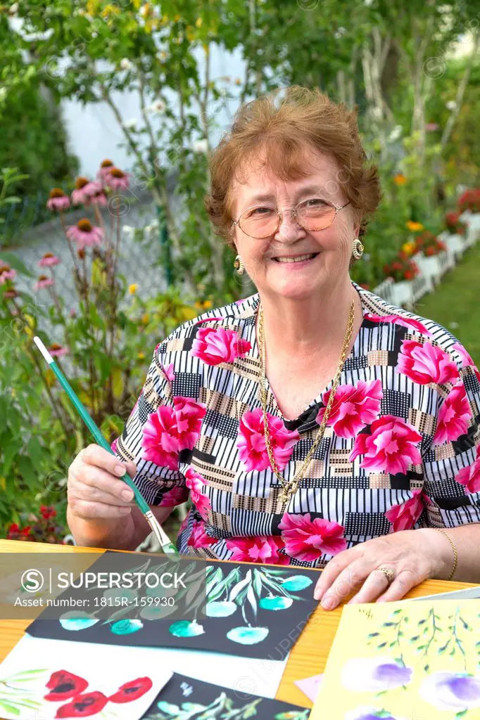 Germany, Bavaria, Ingolstadt, senior woman painting in garden
