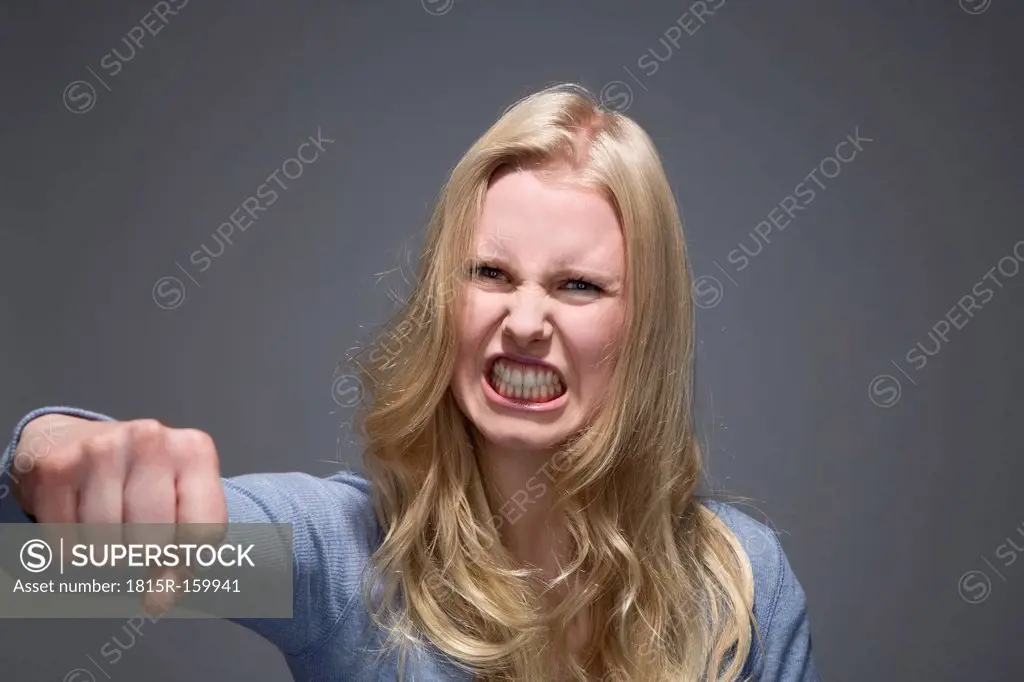 Portrait of furious young woman with outstretched fist and bared teeth