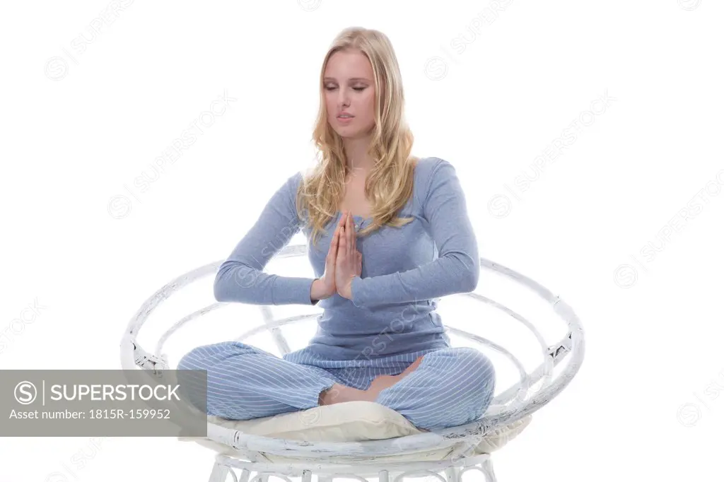 Blond young woman doing yoga exercise in papasan chair