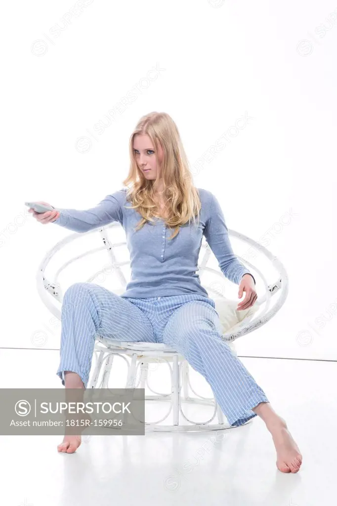 Blond young woman holding remote control in papasan chair