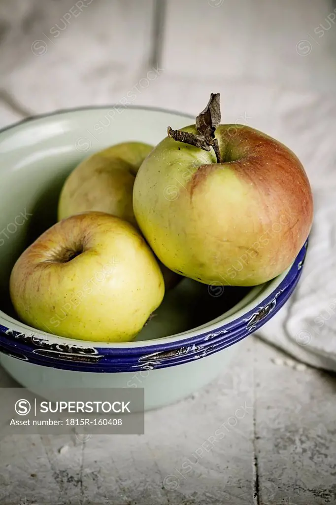 Bowl with three apples on wooden table