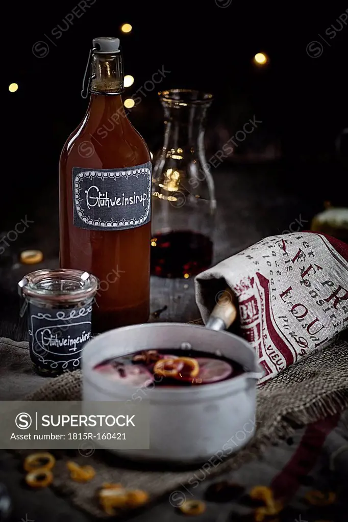 Casserole with mulled wine, slices of lemons and oranges and spices and a bottle with sirup