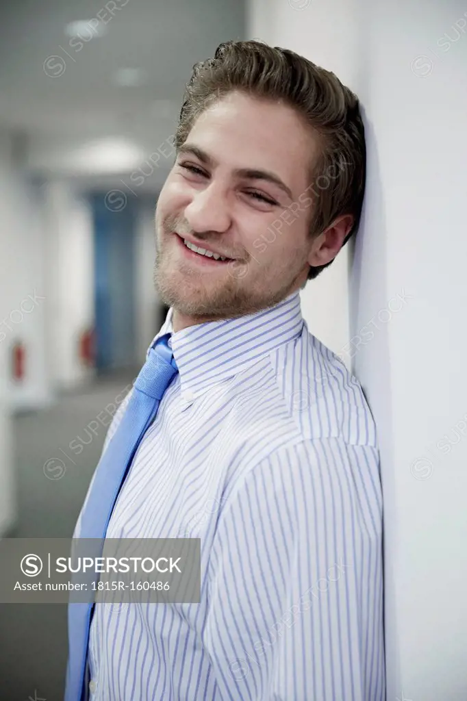 Germany, Neuss, Young business man leaning on wall