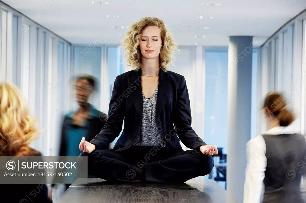 Germany, Neuss, Business woman meditating on desk