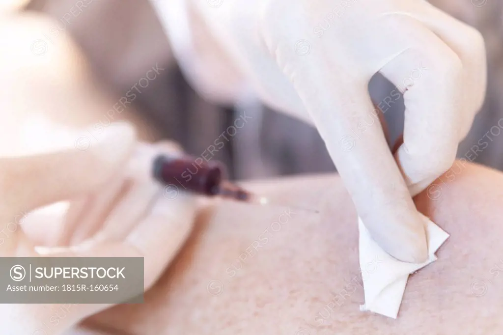 Female alternative practitioner dabing off blood after a blood sample