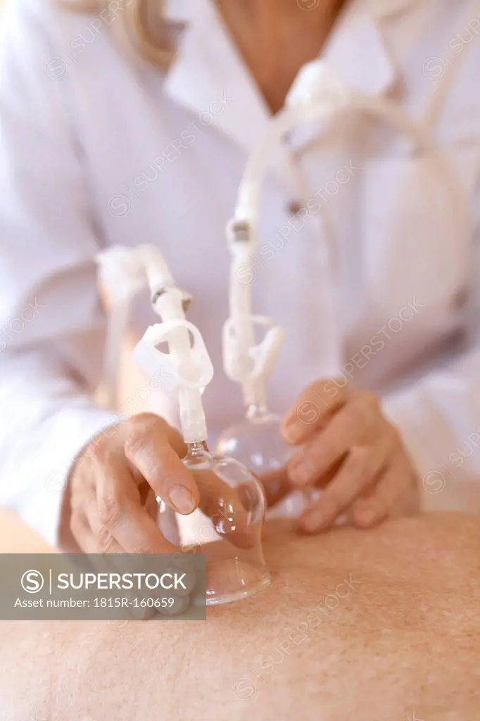 Female alternative practitioner treating senior woman with vacuum cupping therapy