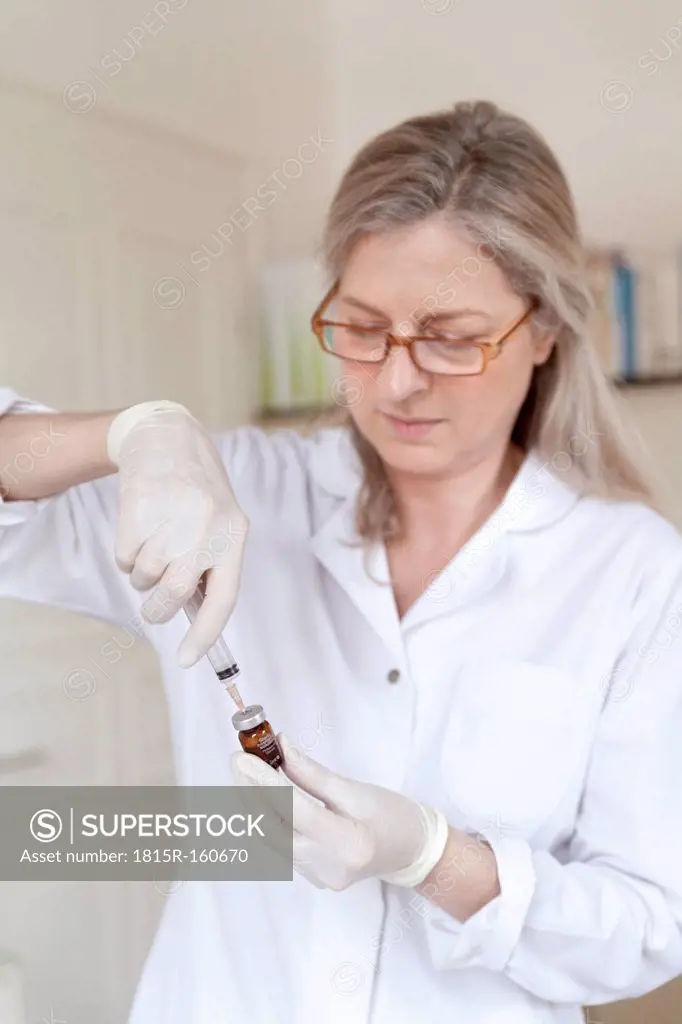 Female alternative practitioner preparing injection syringe