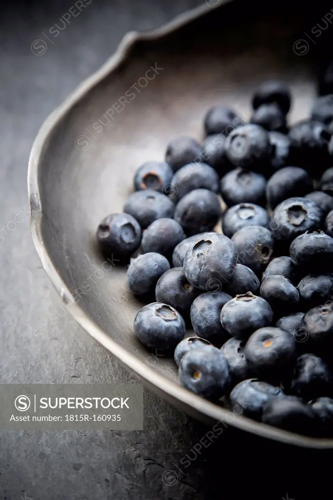 Part of tin bowl with blueberries (Vaccinium myrtillus) on slate