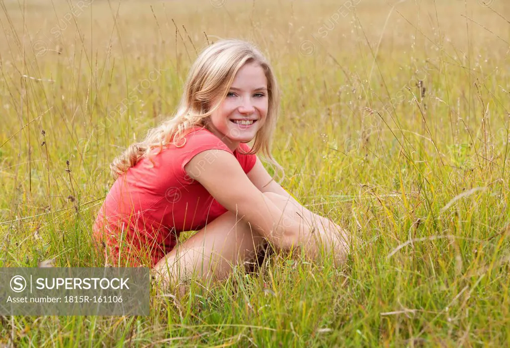 Austria, Salzkammergut, Mondsee, young woman sitting in a meadow