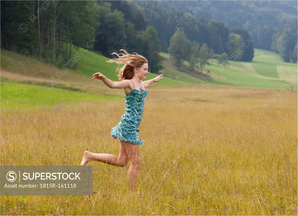 Austria, Salzkammergut, Mondsee, young woman running in a meadow
