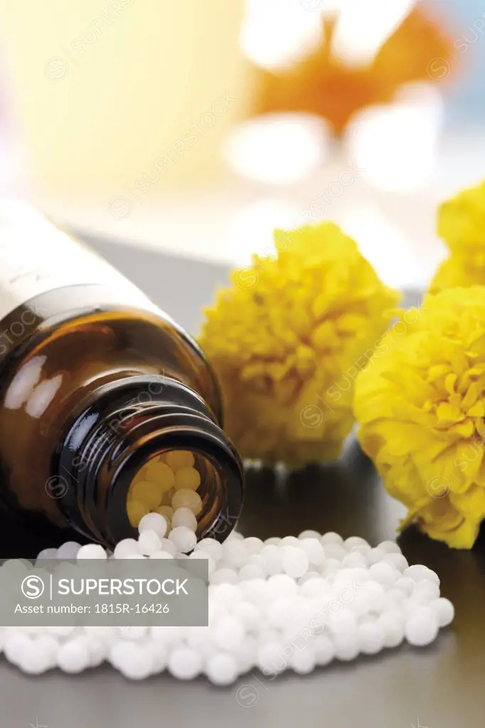 Medicinal flask with pills in front of Tagetes, close-up
