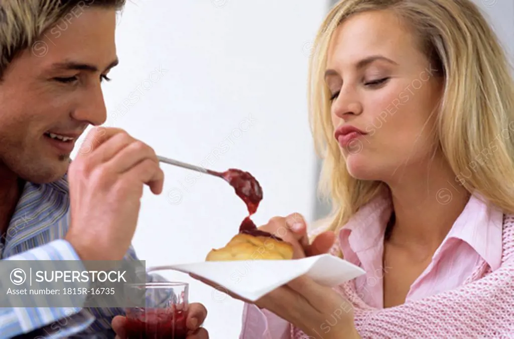 Young couple with cake and jam, close-up