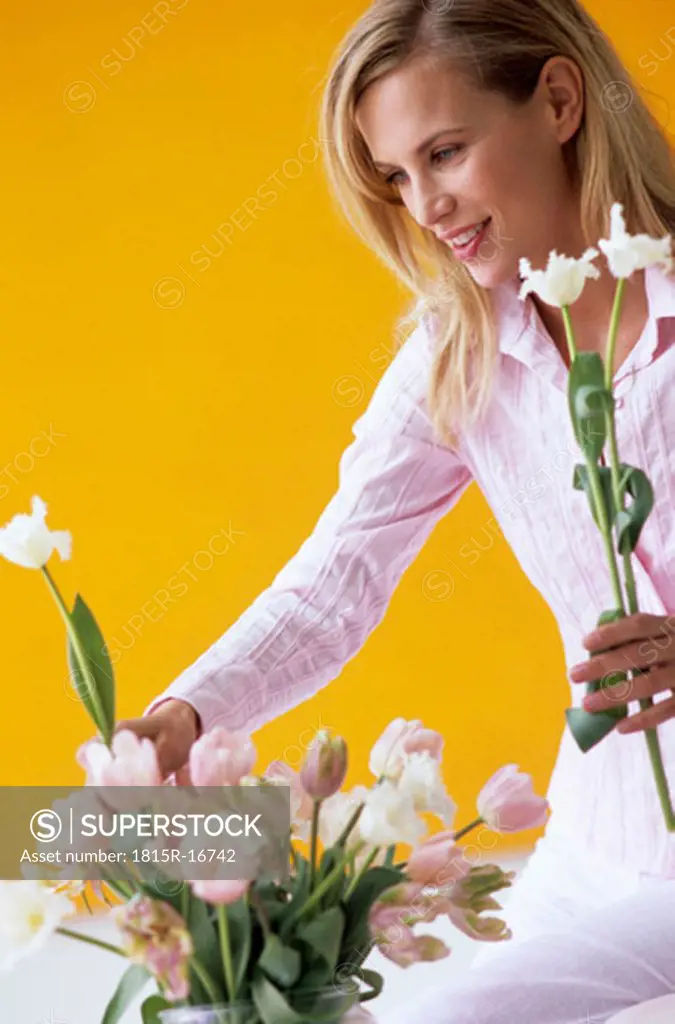 Young woman arranging flowers in vase