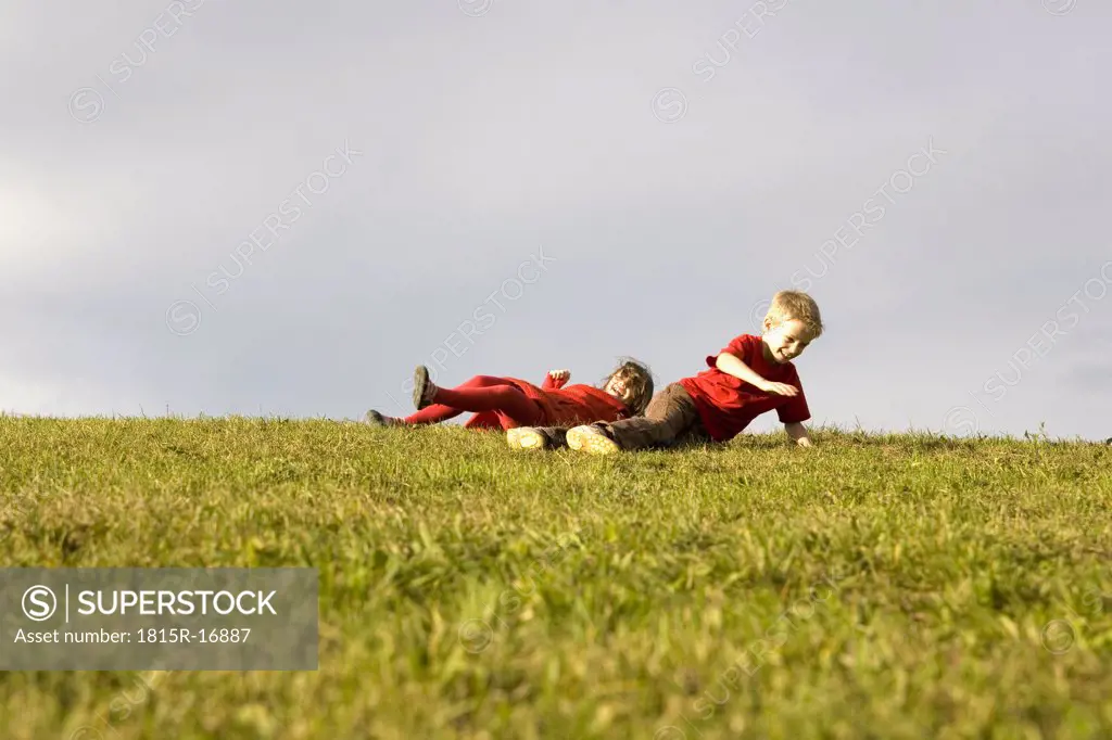 Boy (10-12) and girl (7-9) having fun in meadow