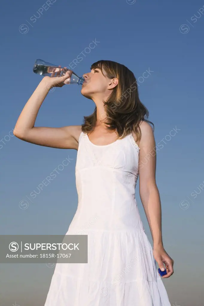 Germany, Bavaria, Young woman drinking water from bottle, portrait