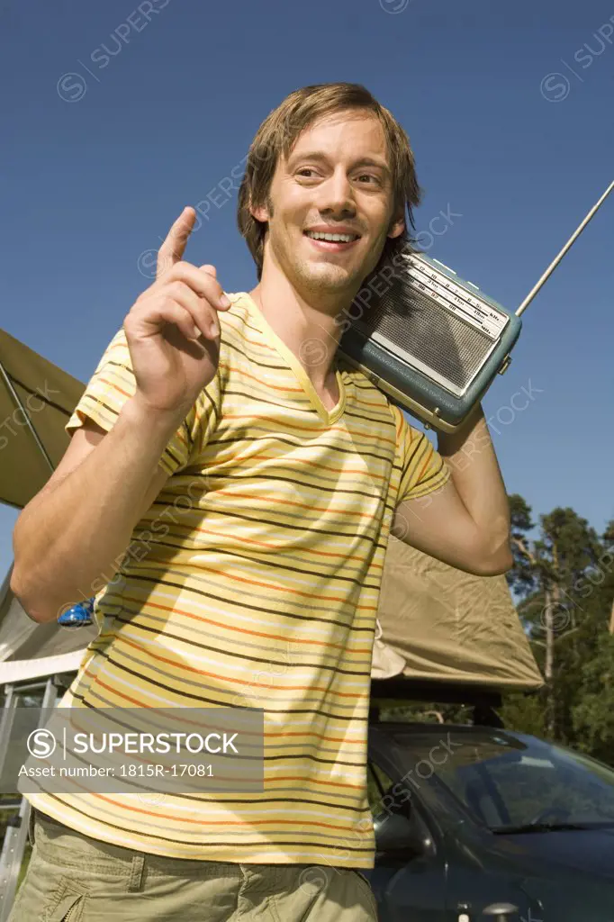 Germany, Bavaria, Young man carrying a transistor Radio on his shoulder