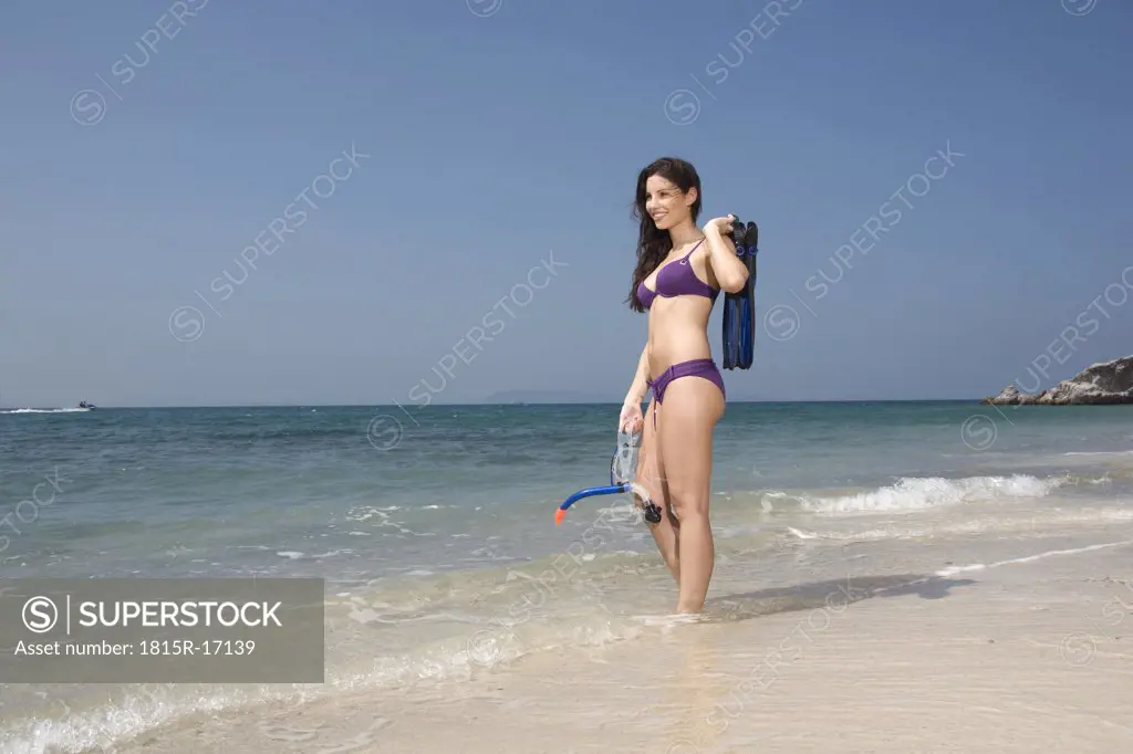 Asia, Thailand, Young woman on beach, holding fins, and diving goggles