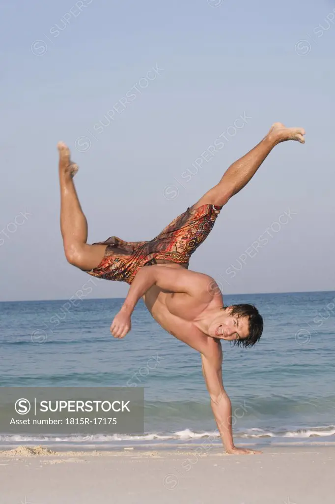 Asia, Thailand, Young man practicing capoeira on beach