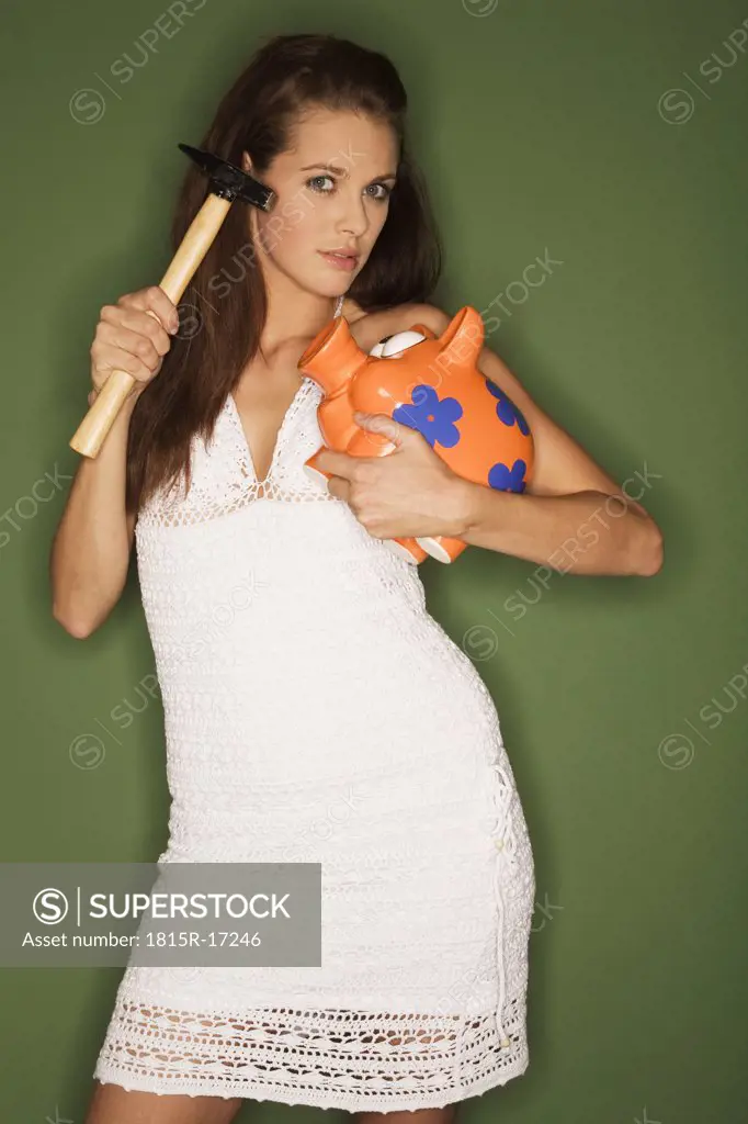 young woman holding piggybank and a hammer