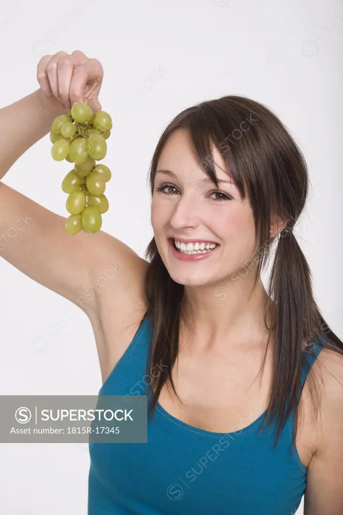 Young woman holding bunch of grapes, portrait