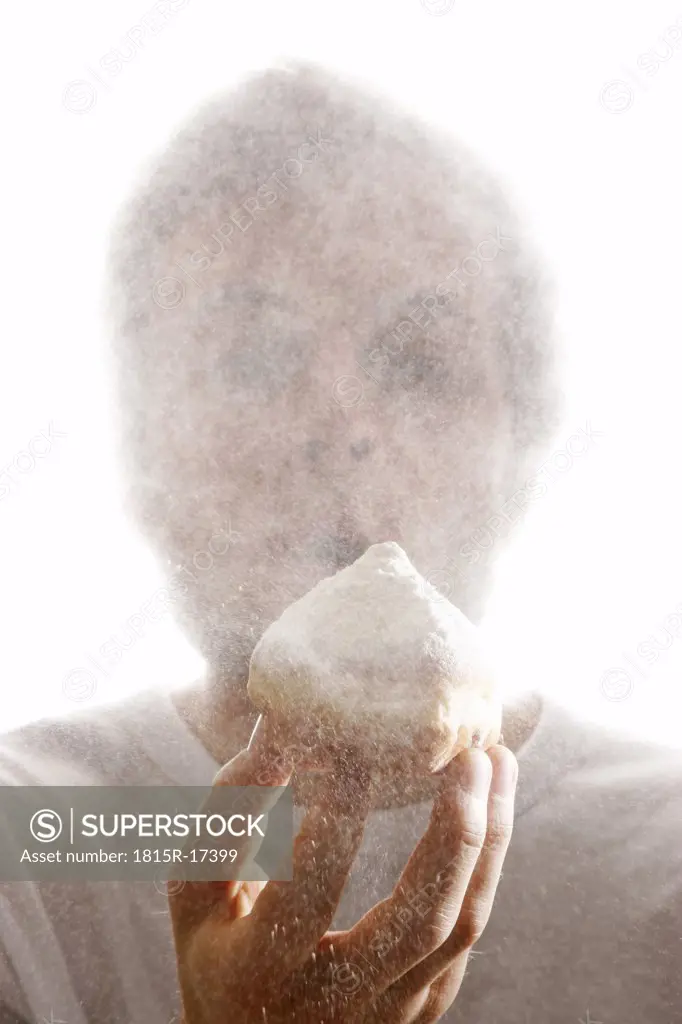 Man, blowing sugar powder from a Krapfen, typical German doughnut