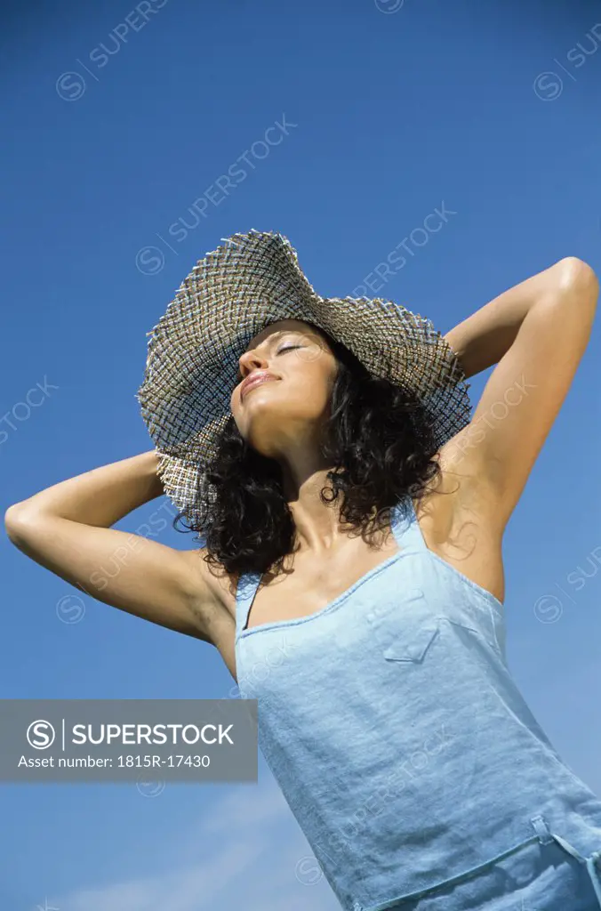 Woman wearing hat with eyes closed, low angle view