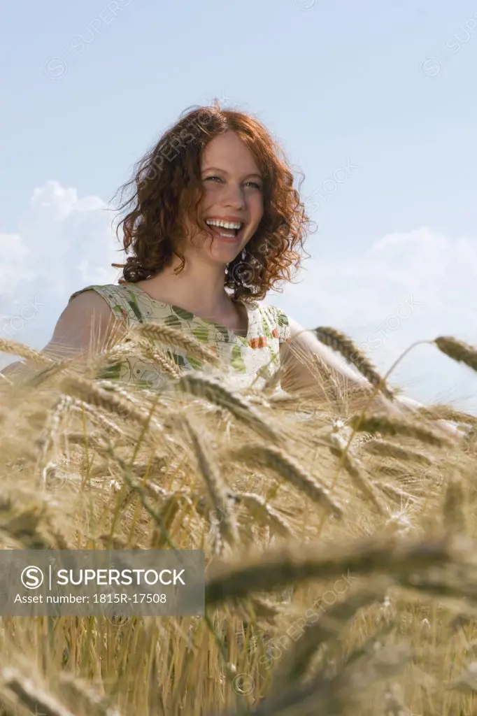 Young woman standing in cornfield, smiling