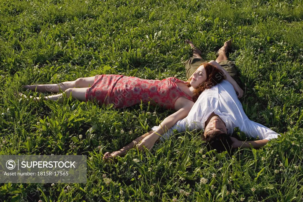 Woman lying with head on man`s belly in meadow