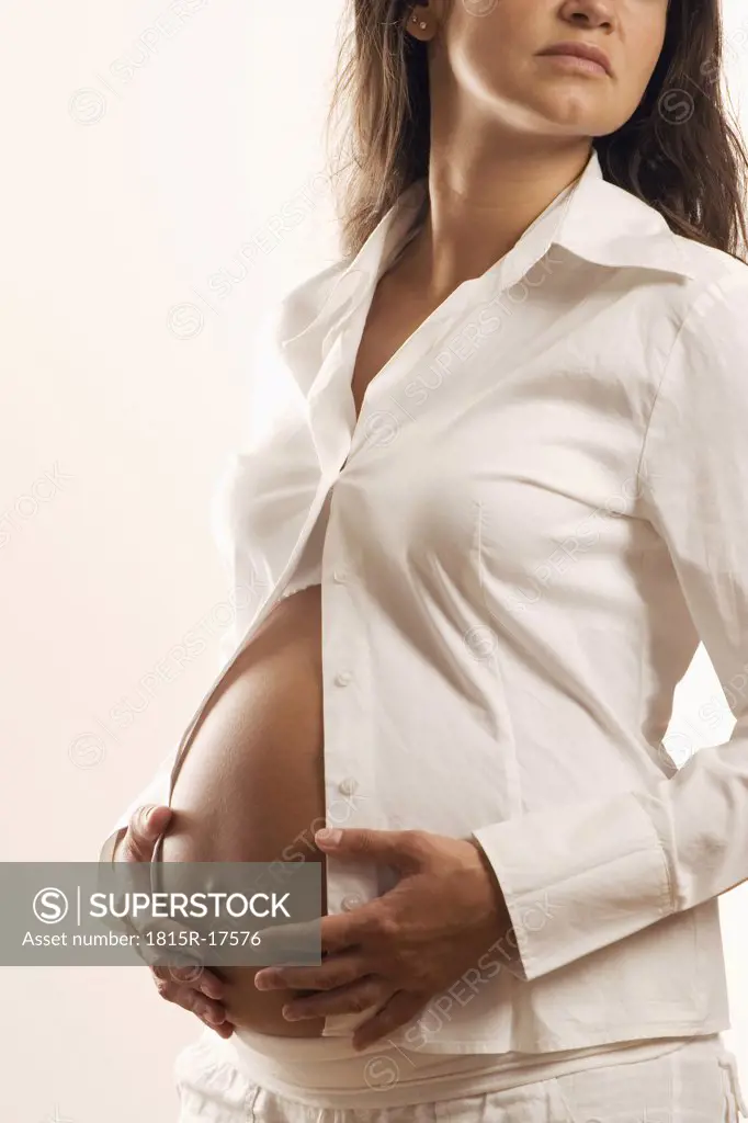 Pregnant woman, hands on belly, mid-section,