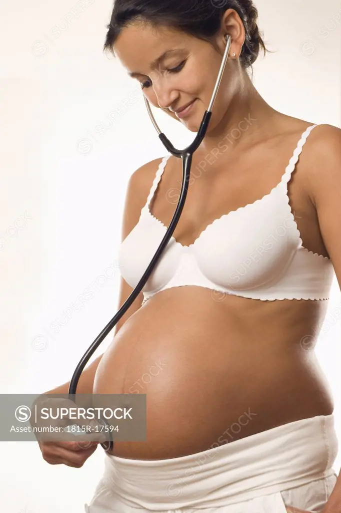 Pregnant woman holding stethoscope on belly, close up