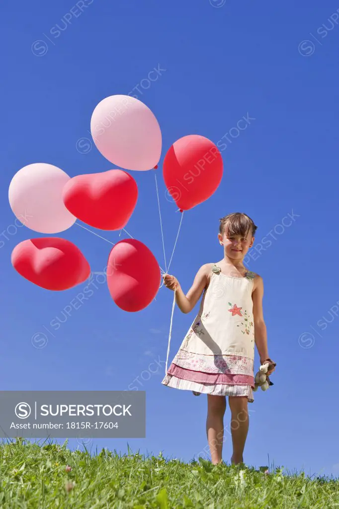 Girl (7-9) holding bunch of ballons